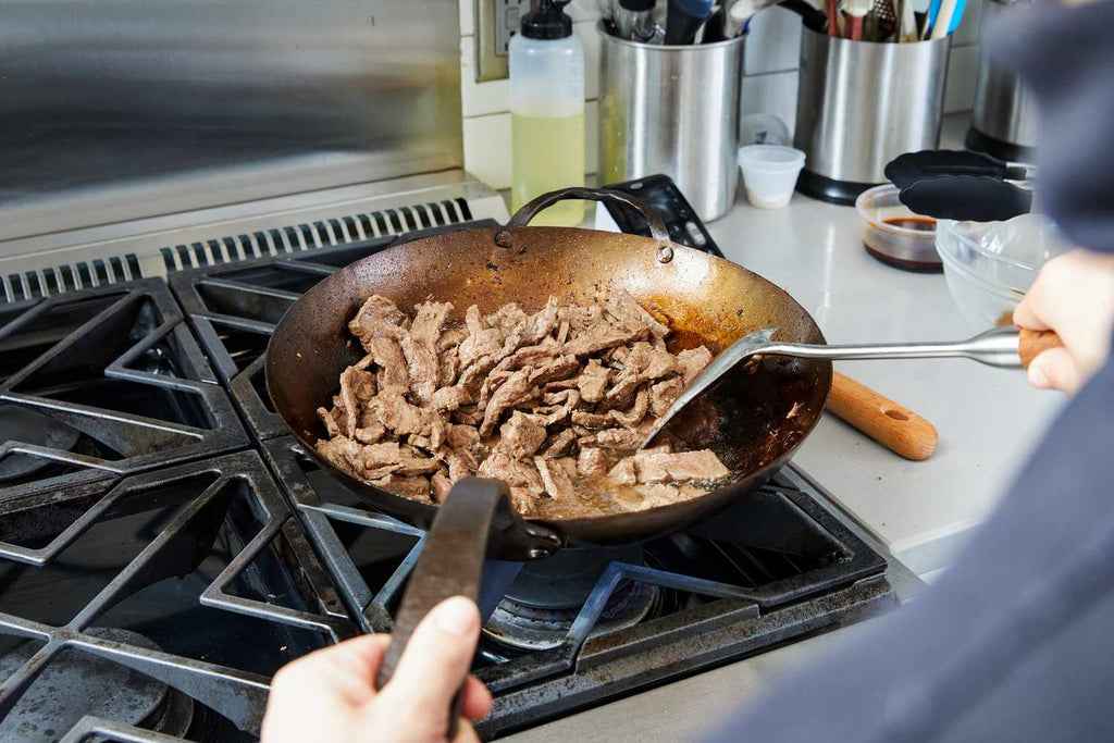 Why is it important to season a wok for perfect grilling?